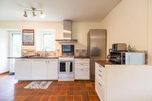 eine große Küche mit weißen Schränken und Geräten in der Unterkunft Charmante maison la Tissanderie a Saint-Carreuc in Saint-Carreuc