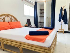 a bedroom with a large bed with orange and blue pillows at VaoVao Hotel in Nosy Be