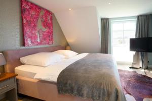 a bedroom with a bed and a painting on the wall at Ferienhaus Sylt Leev in Westerland