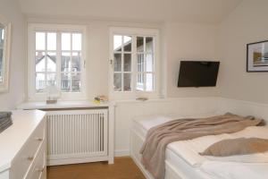 a white bedroom with a bed and a flat screen tv at Ferienwohnung Tau Hus Keitum Sylt in Keitum