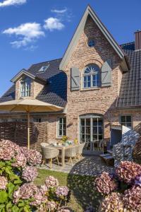 une maison avec un patio avec une table et des chaises dans l'établissement Ferienhaus Sylter Schönheit, à Westerland