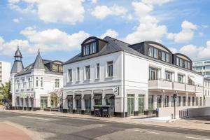 a white building with a black roof on a street at Exklusives Apartment Turmkoje im Herzen Westerlands in Westerland (Sylt)
