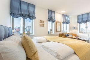 a bedroom with a large bed with blue curtains at NEU! Ferienwohnung Deck 2 - exklusives Apartment in zentraler Lage in Westerland (Sylt)