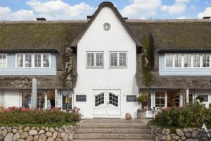 une maison blanche avec un toit en gazon dans l'établissement Ferienwohnung Luettje Moehl - Kleines Paradies am Wattenmeer in Keitum Sylt, à Keitum