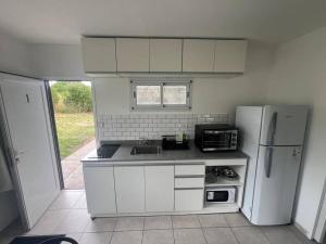 a kitchen with white cabinets and a white refrigerator at EKÜ Chapa Tiny House - Playa Luna Roja in La Estafeta