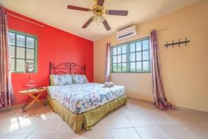 a bedroom with red walls and a bed and a ceiling fan at Palma Real 28 - 2-Bedroom Vacation Condo in Palm Beach, Aruba in Palm-Eagle Beach