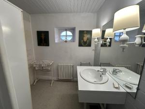 Un baño blanco con lavabo y espejo. en Chambres et table d'hôtes Maison Garesché, en Nieulle-sur-Seudre 39 fotos más