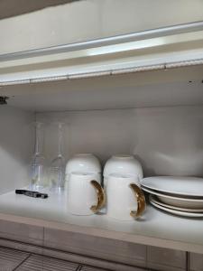 a white cabinet with plates and glasses and a toilet at Wooyeon in Seongnam
