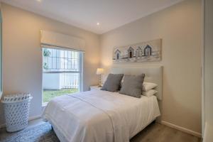 a bedroom with a white bed and a window at 4198 River Club in Plettenberg Bay +8 photos