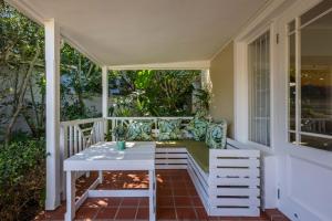 a porch with a white table and a couch on it at 4198 River Club in Plettenberg Bay