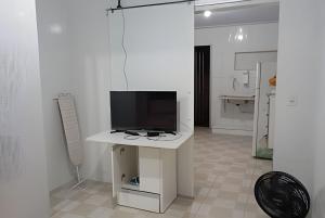 a living room with a tv on a white table at kitnet 01 preço popular in Brasília