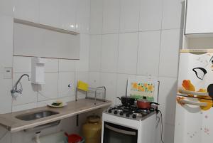 a white kitchen with a stove and a sink at kitnet 01 preço popular in Brasília +7 photos