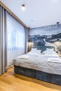 a bedroom with a large bed with a painting on the wall at Apartamenty Tatra Lux in Bukowina Tatrzańska +80 photos