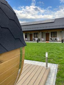 a house with a wooden deck with a yard at Leśne Apartamenty in Bobolice