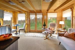 un ampio soggiorno con pareti e finestre in legno di Vineyard lodge in Herefordshire a Ledbury