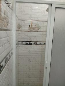 a bathroom with a shower with white brick walls at Appartement bien équipé et calme in Tangier +11 photos