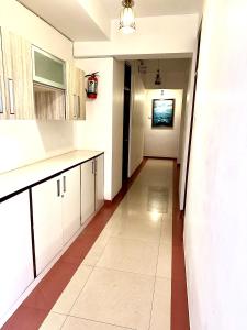 a kitchen with white cabinets and a long hallway at Hotel El - Paso in Arambol