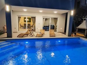 a house with a swimming pool with chairs and a table at Vila MaMe apartman s privatnim bazenom, besplatnim parkingom i wi - fi in Kaštela