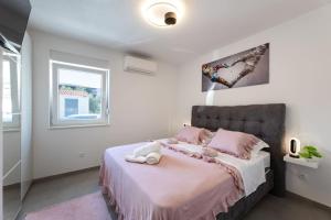 a bedroom with a bed with pink sheets and a window at Vila MaMe apartman s privatnim bazenom, besplatnim parkingom i wi - fi in Kaštela +22 photos