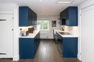 a kitchen with blue cabinets and white counters at 3 bed penthouse above quaint pub in Matfield