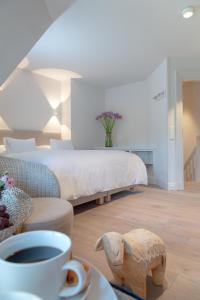 a bedroom with a bed and a table with a cup of coffee at NEU Dorfhues Anja friesisch modern urlauben in Kampen Sylt in Kampen
