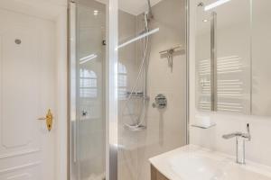 a white bathroom with a shower and a sink at Ferienwohnung Waterkant in Munkmarsch