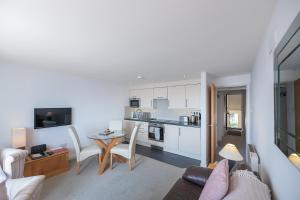 a living room with a couch and a table and a kitchen at Fabulous Sea View Apartment in Aberdyfi