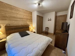 - une chambre avec un lit et un mur en bois dans l'établissement Appartement cosy 3 pièces, avec balcon et piscine, proche des pistes et commodités à La Plagne Tarentaise - FR-1-353-118, à La Plagne Tarentaise