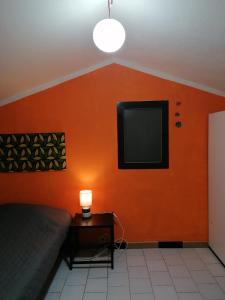 sypialnia z pomarańczową ścianą i telewizorem z płaskim ekranem w obiekcie Appartamento vista mare con terrazza Bosa Turas w mieście Magomadas