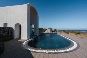 a swimming pool next to a building with the ocean at Danae Suites Santorini in Oia