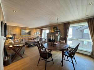 Una sala de estar con una mesa y sillas y un sofá. en Kikut Panorama Geilo Ski-in Ski-out, en Geilo