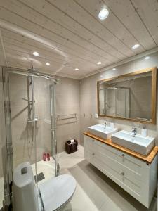 Un baño con dos lavabos y una ducha y un inodoro. en Kikut Panorama Geilo Ski-in Ski-out, en Geilo 26 fotos más