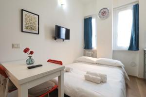 a room with two beds and a desk and a tv at Primopiano - Avogadro in Milan
