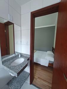 Un baño con lavabo, espejo y cama. en Pousada Estrela Mares Suíte 208, en Cabo Frío