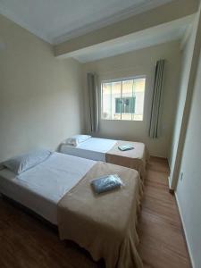 Dos camas en una habitación con ventana. en Pousada Estrela Mares Suíte 208, en Cabo Frío