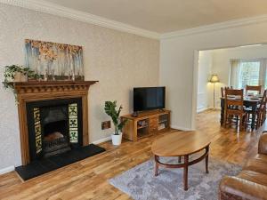 a living room with a fireplace and a television at Lavender Lodge in Burbage