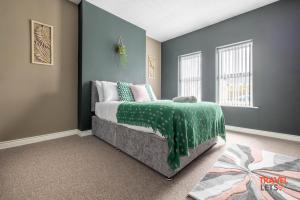 ein Schlafzimmer mit einem Bett mit einer grünen Decke in der Unterkunft Coastal Cottages in Ballycastle