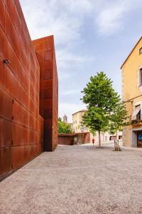 una gran pared de ladrillo rojo junto a un árbol en Bravissimo Apartaments Mora 4, en Girona