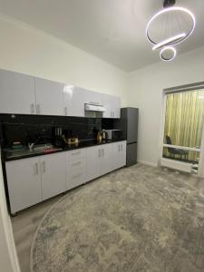 una cucina con mobili bianchi e un piano di lavoro nero di Жилой комплекс Al-Farabi a Shymkent