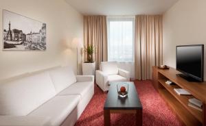 a living room with a white couch and a tv at Clarion Congress Hotel Olomouc in Olomouc