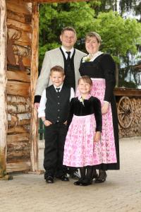 a family posing for a picture in front of a cabin at Gasthaus Goglhof in Fügenberg