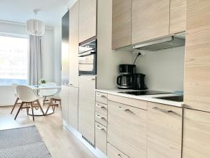 Una cocina con gabinetes de madera y una mesa en ella. en City Home Finland Arena Studio - Perfect location in Downtown of Tampere and Great Amenities, en Tampere