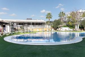 a swimming pool with a fountain in the grass at Camping El Torres in Villajoyosa
