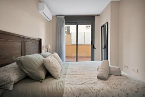 ein weißes Schlafzimmer mit einem großen Bett mit Kissen in der Unterkunft Apartamento con terraza y piscina en Puerto Marina - MISTRAL in Benalmádena + 28 Fotos