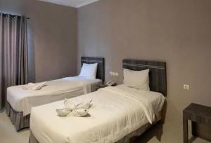 Dos camas en una habitación de hotel con flores en ellas. en A'rabia Style Hotel Sriwijaya, en Medan