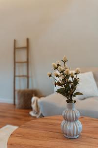 a white vase with flowers on a wooden table at Spacious, newly renovated loft - 107m2 in Sint-Niklaas