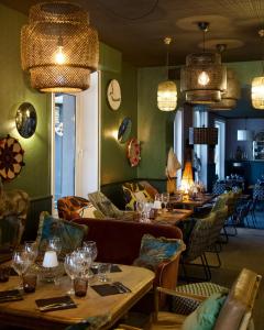 a restaurant with long tables and chairs and chandeliers at Hôtel des Pins in Jullouville-les-Pins