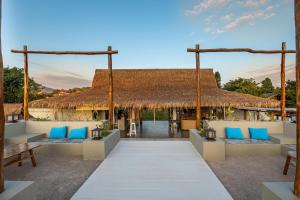 un patio esterno con sedie blu e tetto di paglia di The Sanctuary Nam Ngum Beach Resort a Vang Vieng