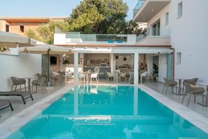 an outdoor patio with a pool and tables and chairs at Margaida Boutique Hotel & SPA in Cala Gonone