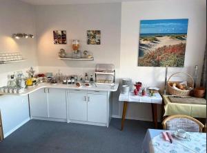 a kitchen with white cabinets and a painting on the wall at Zweibettzimmer-03-EG in Borkum